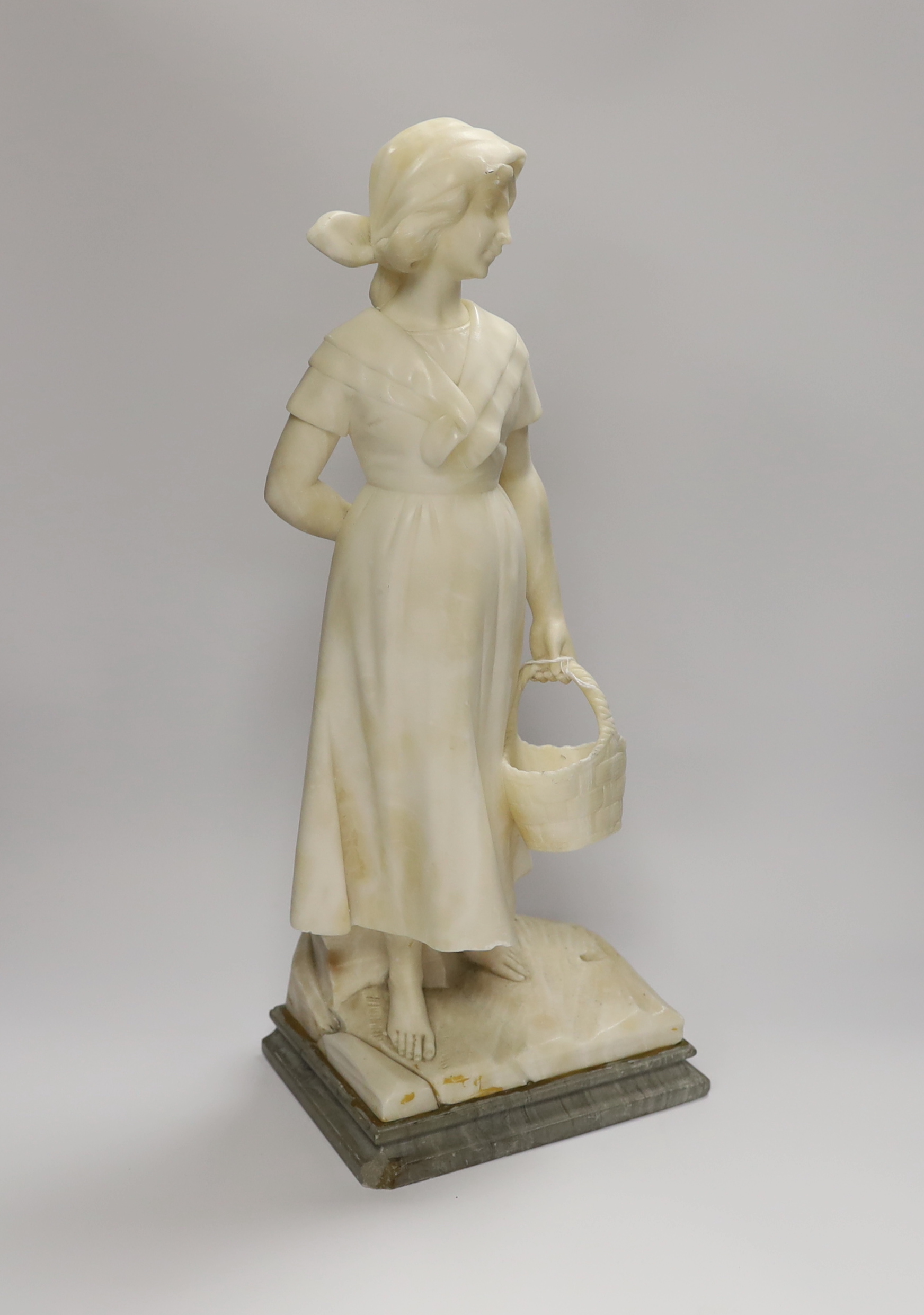 An early 20th century alabaster carved figure of a girl holding a basket, 51cm high